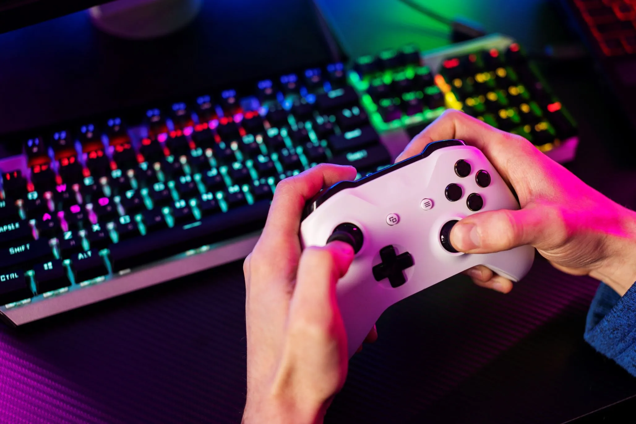 Mãos segurando console de video game com teclado colorido