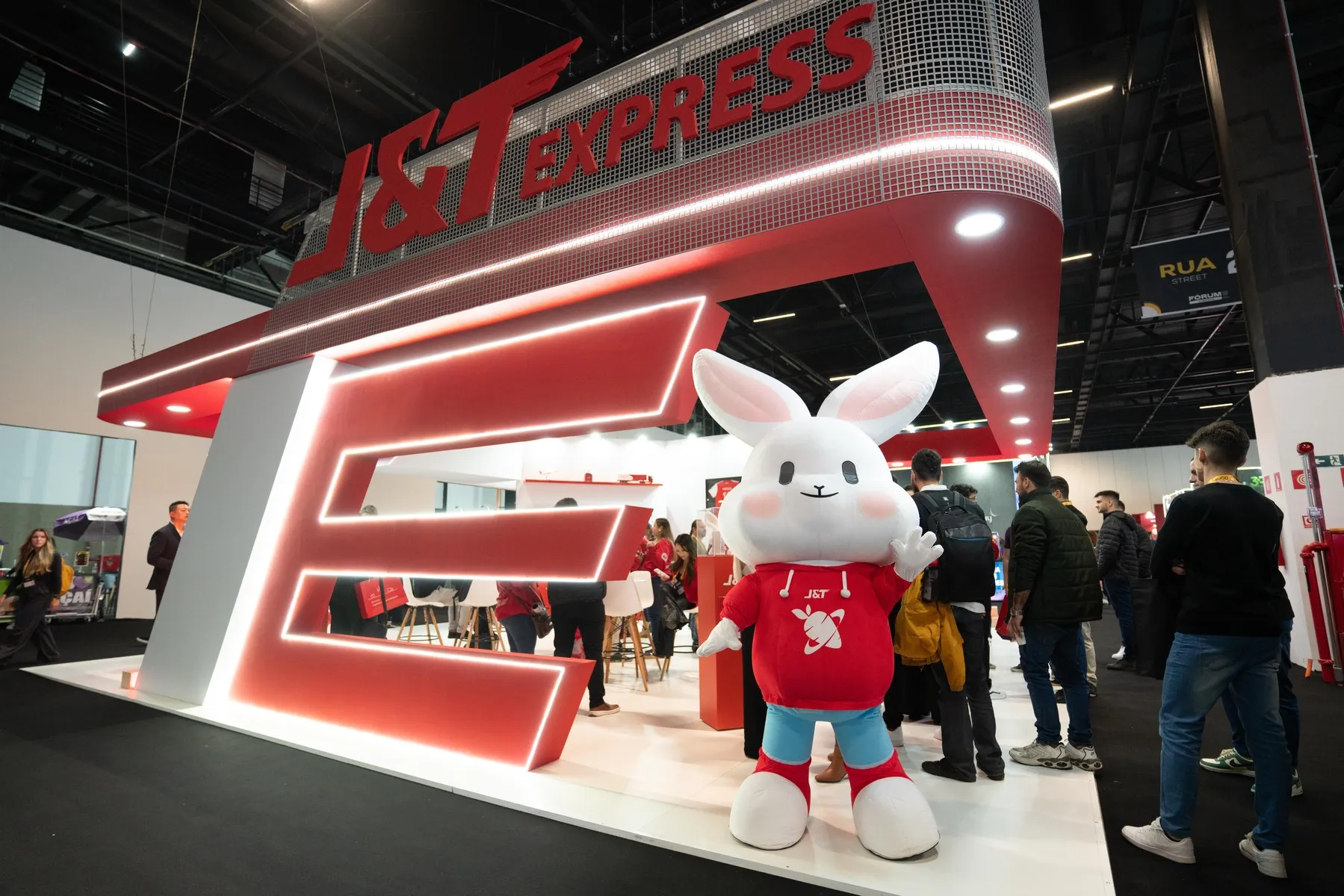 Estande da J&T Express no Fórum ECBR '24 com Mau Mau (coelho, mascote da marca) em frente