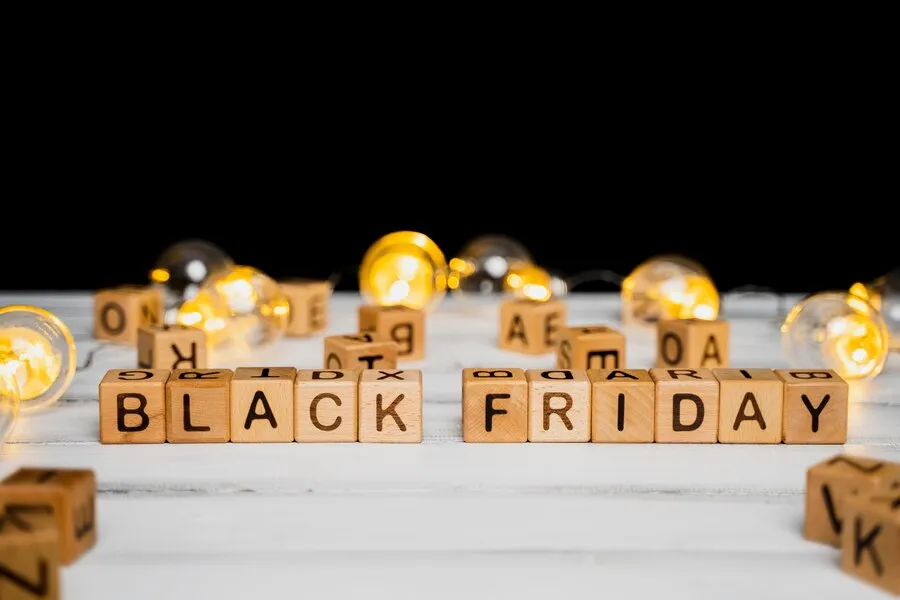 Cubos de madeira com Black Friday escrito em cima de mesa com luzes de decoração atrás