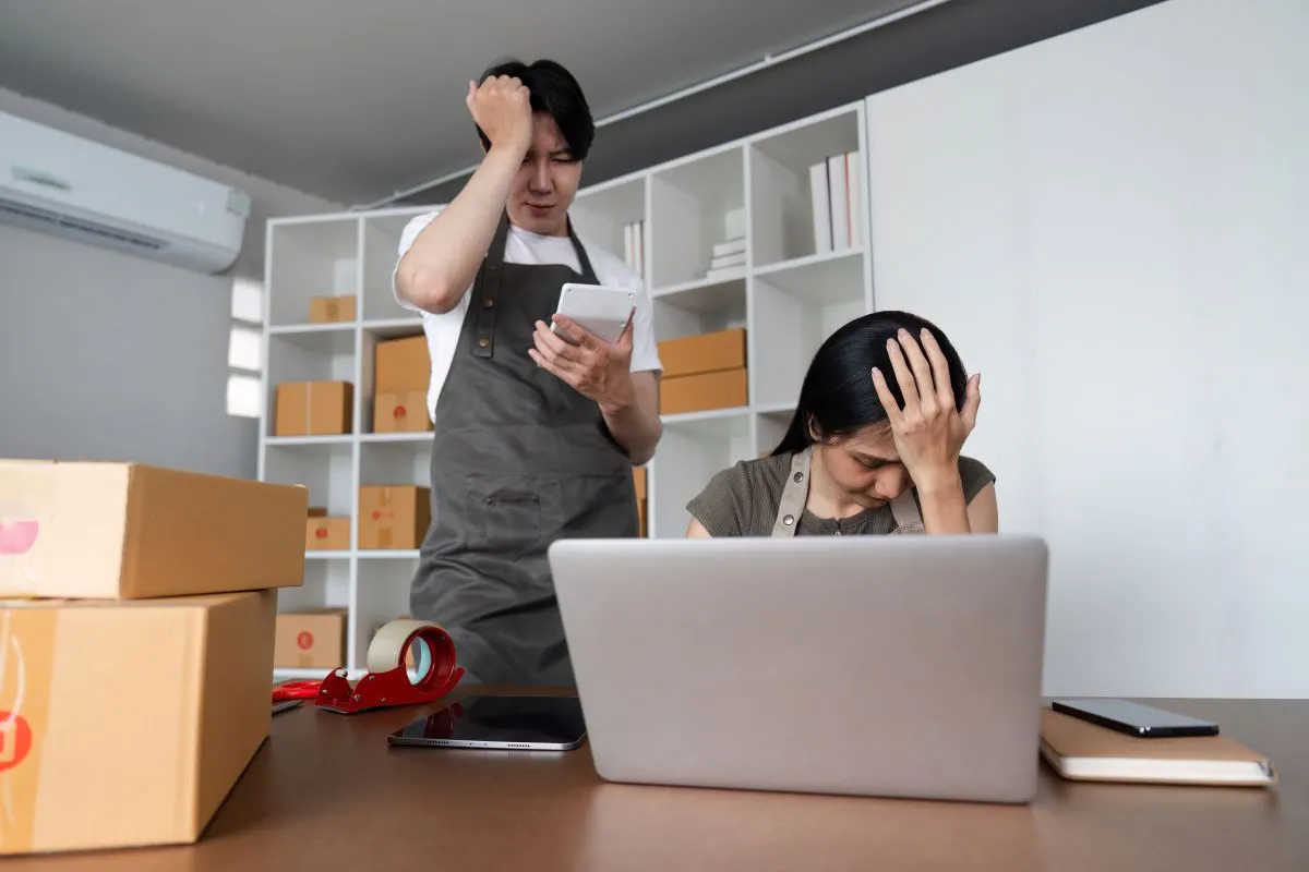 Casal estressado analisando dados do mercado de ações on-line em casa com laptop e smartphone