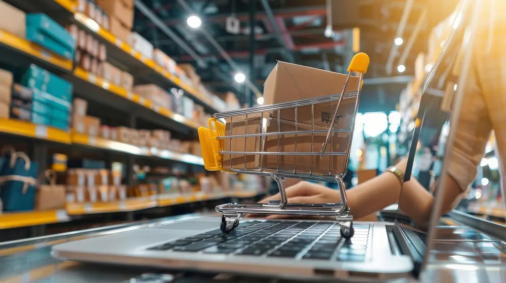Carrinho de compras em cima de um laptop em um depósito.