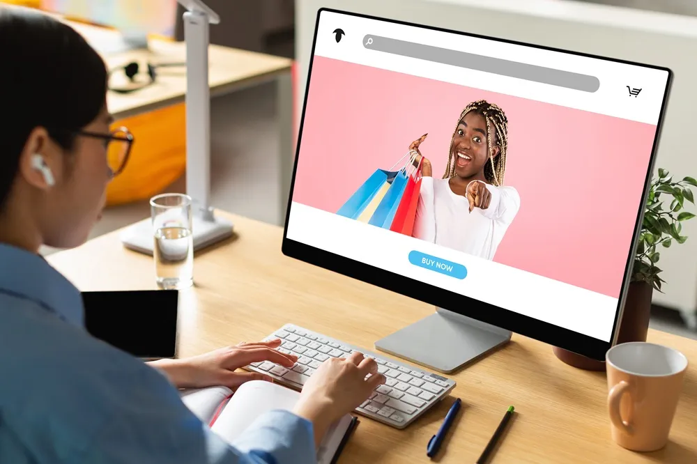 Usuária em frente a um computador visualizando uma oferta personalizada de compras online com botão “Buy Now”.