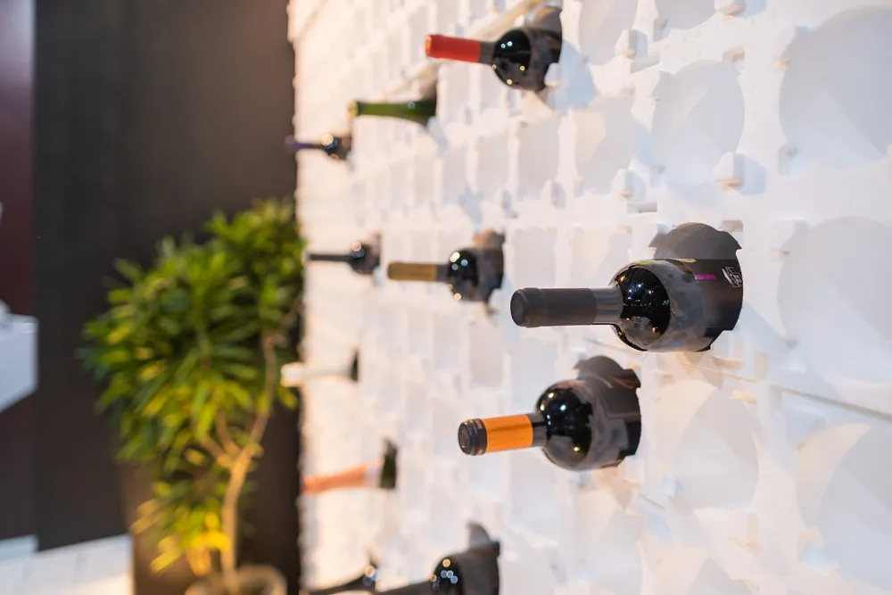 Garrafas de vinho em painel de parede branco com encaixes modulares.