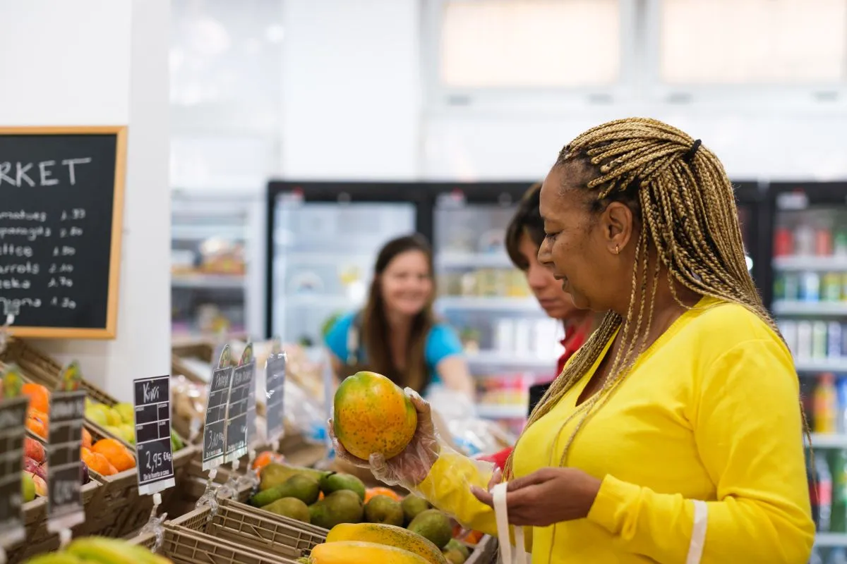 Mulher adulta comprando frutas e vegetais no mercado