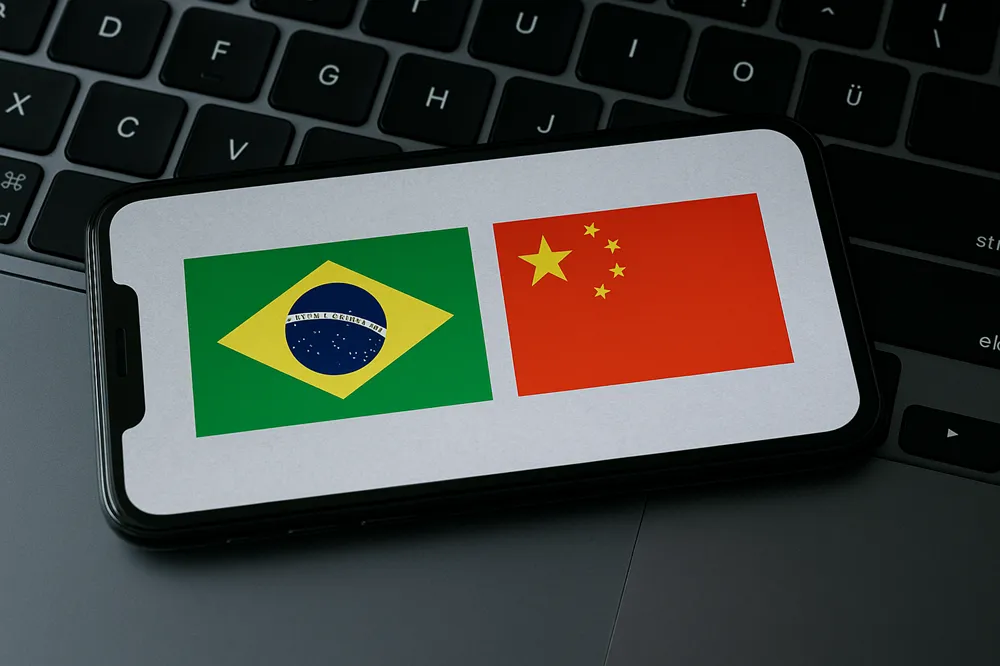 Smartphone sobre um teclado exibindo lado a lado as bandeiras do Brasil e da China na tela.