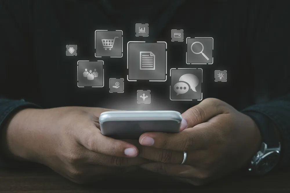 Pessoa segurando celular com ícones digitais flutuando.