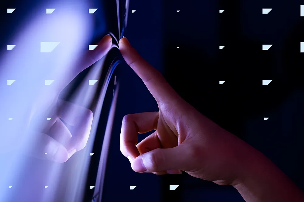 Mão tocando uma tela iluminada em tons azul e roxo, com reflexo e clima futurista.